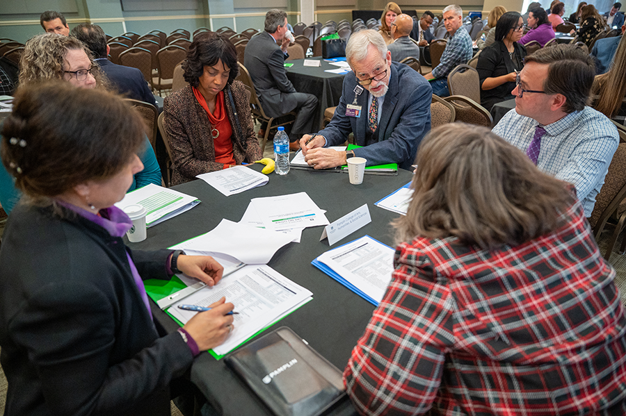 people sitting around a table talking in a large meeting room