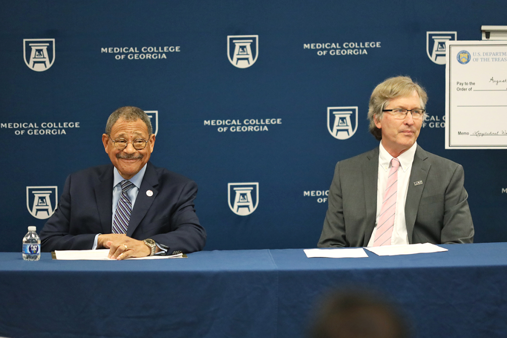 two men sit at a table for a presentation