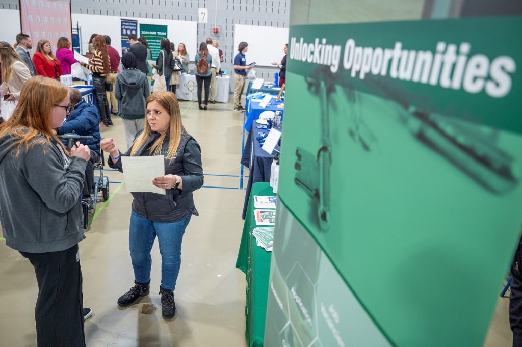 Two women talk at a job fair