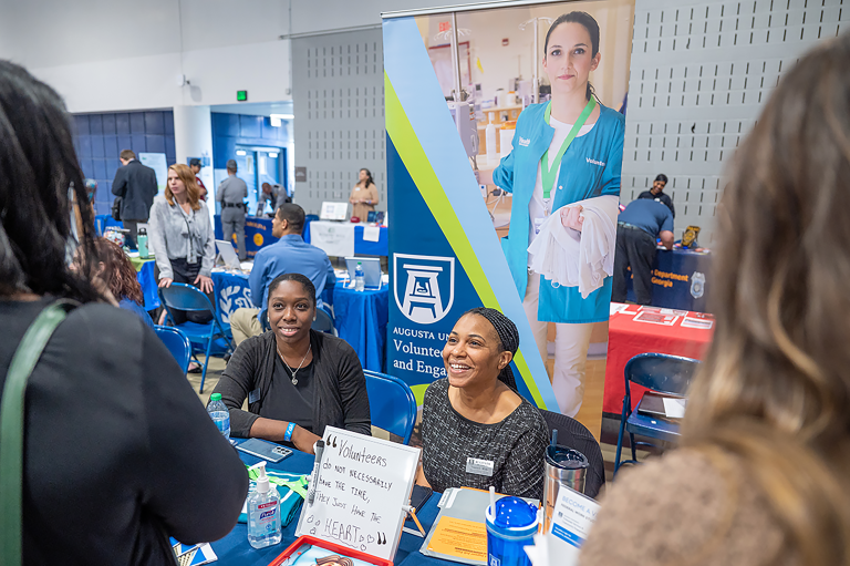 women at a table talking to students at the Jaguar Job Fair