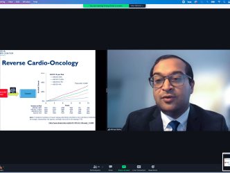 Split screen with powerpoint presentation on cardio oncology on left, man in black suit with glasses on right.