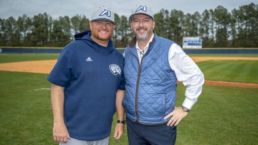 Two men smiling on a baseball field