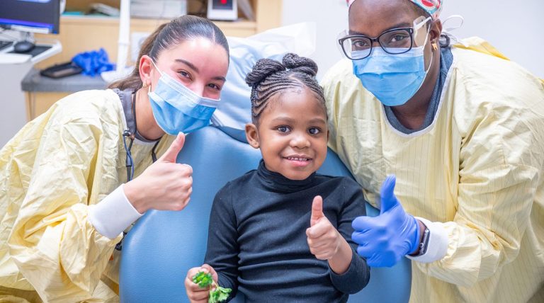 Dr. Ana Phillips and dental assistant Ashley Roberts pose for a photo with their patient.