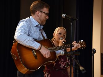 Man playing a guitar while a woman sings
