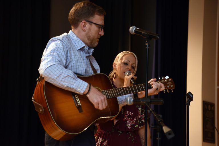 Man playing a guitar while a woman sings