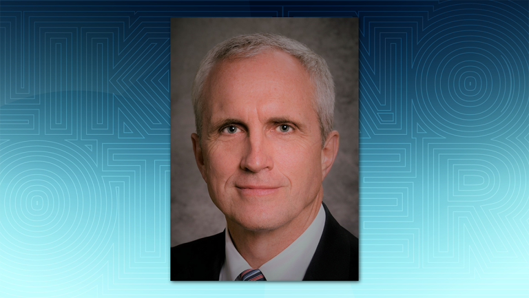 Man in black suit and striped tie in front of a textured background