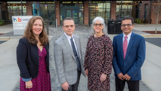 Four people stand in front of building smiling