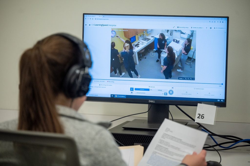 woman observes students on a computer monitor