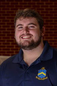 man smiling while wearing a blue polo shirt