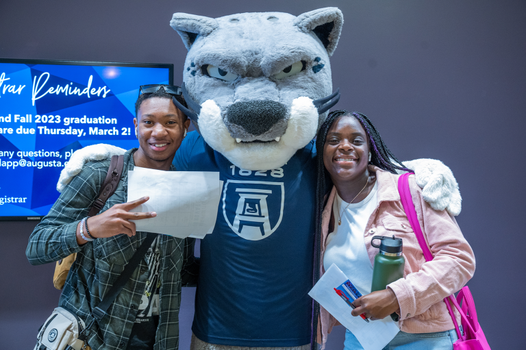 woman and man standing by Augustus the mascot