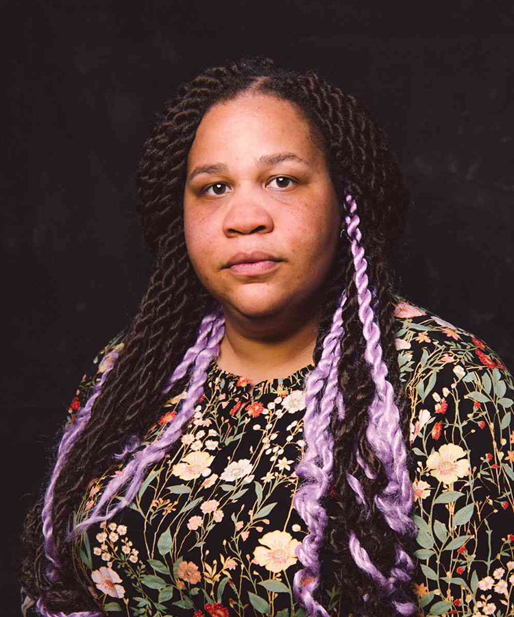 woman with braids stands in front of a black background