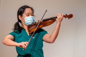 woman in scrubs playing violin