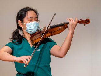 woman in scrubs playing violin