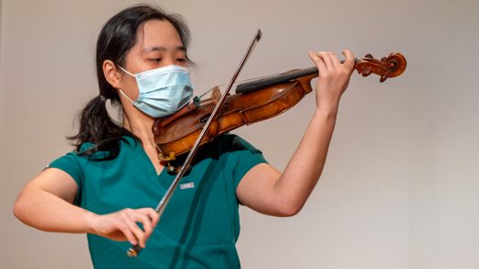 woman in scrubs playing violin