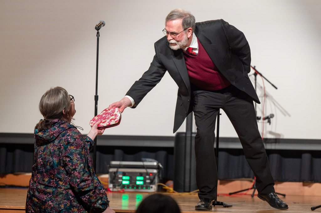 man on stage giving a woman a gift