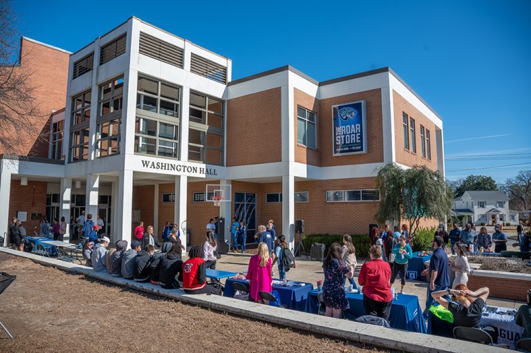People sitting on the patio to the Roar Store.