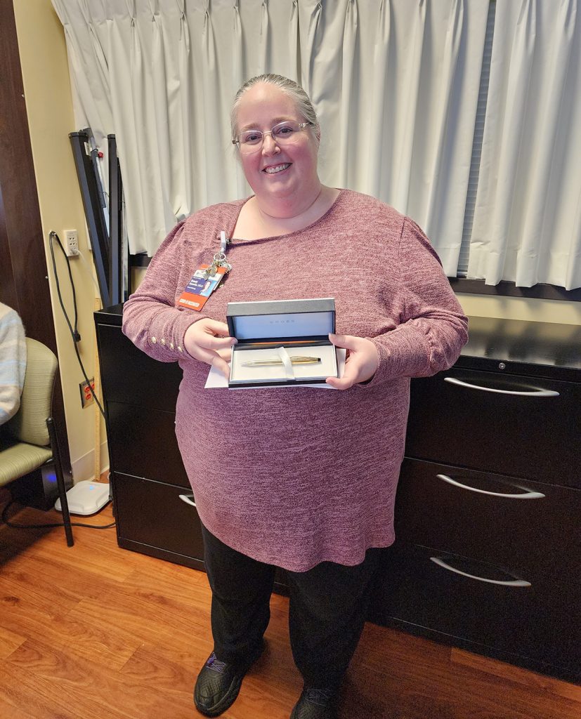 woman standing with a golden pen award
