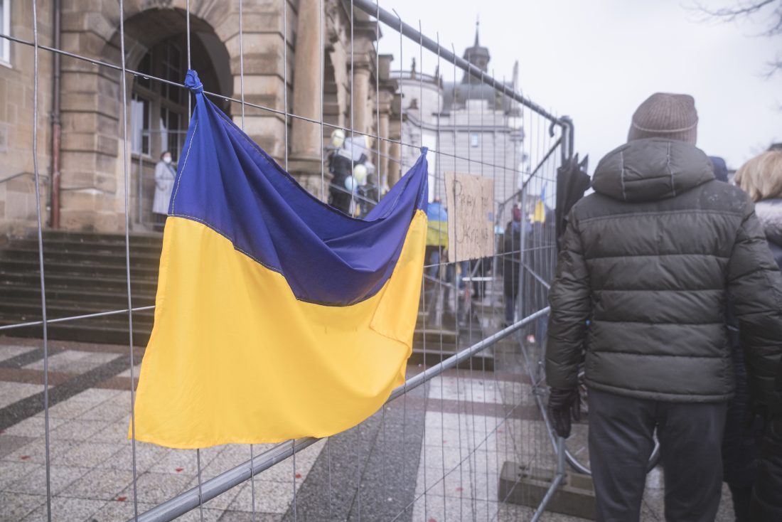 Ukraine flag is hung on a fence in front of a building