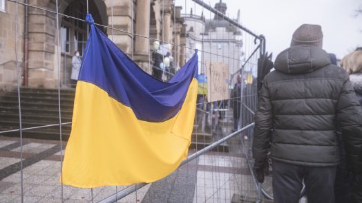 Ukraine flag is hung on a fence in front of a building
