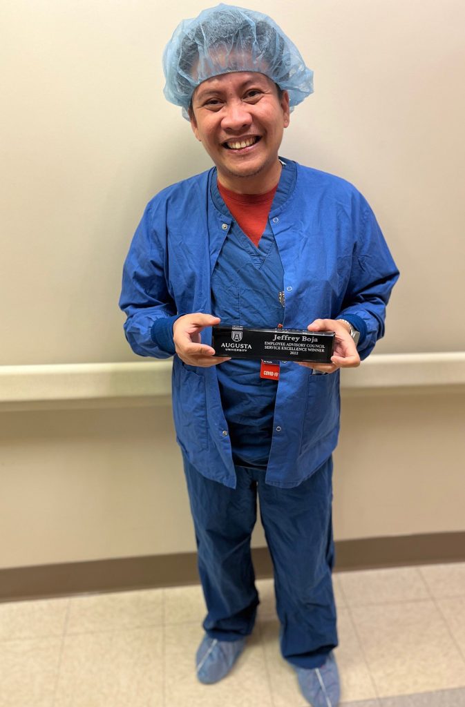 Man in scrubs standing with an award