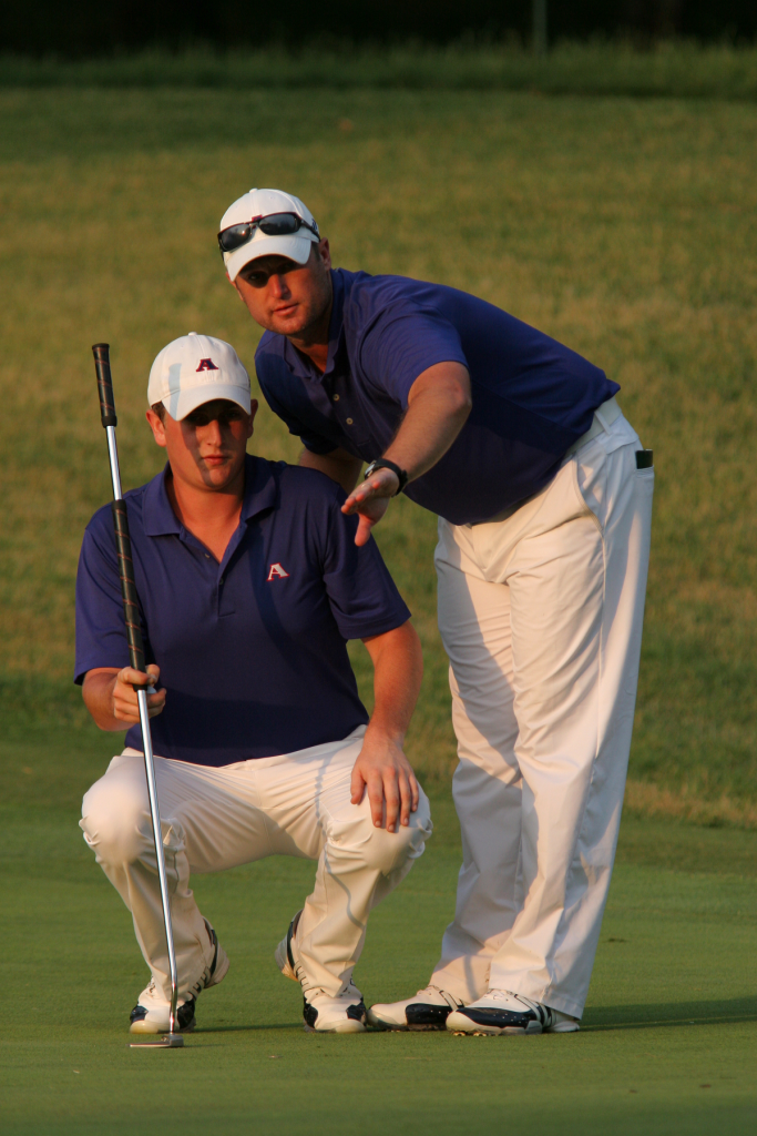 Golf coach and player look over a putt