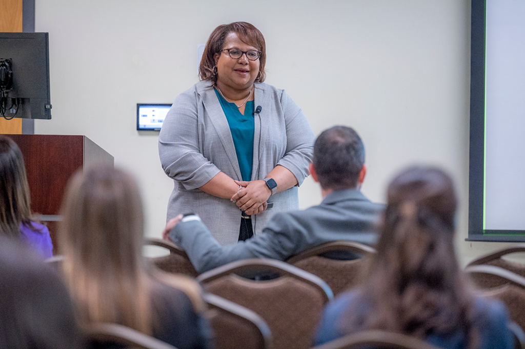 Woman presents to a room full of people.