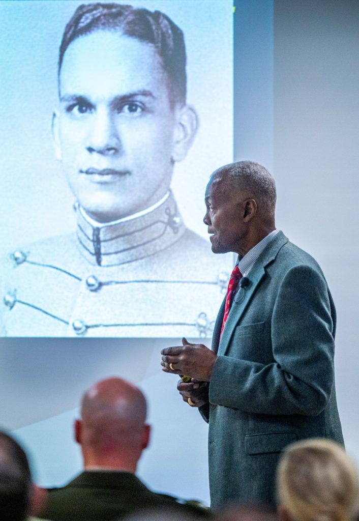 man giving a speech in front of a a projection screen