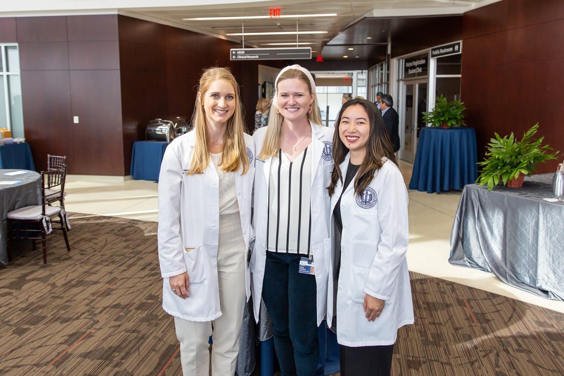 Female dental students in white coats smiling