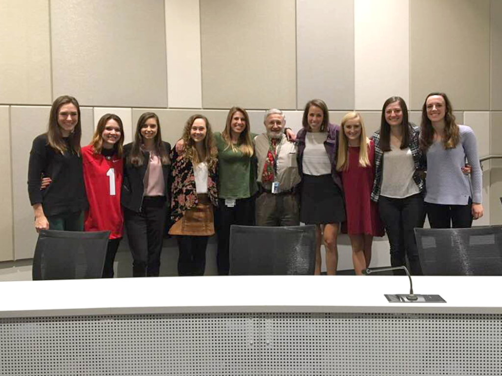 man stands with a group of nine women for a photo