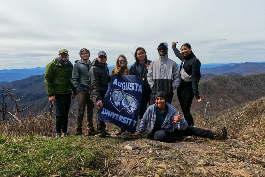 group of people standing on top of big hill with a mountain in the background