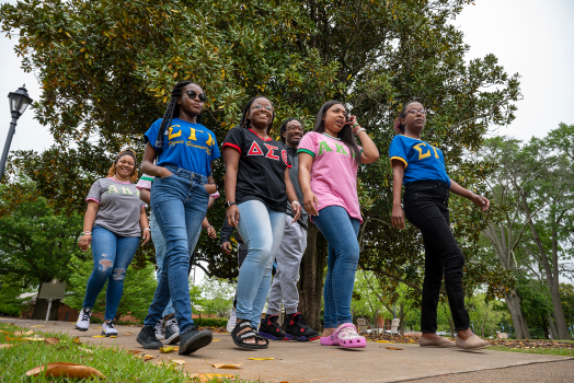 women and men walking outside of the Summerville Campus wearing fraternity and sorority attire