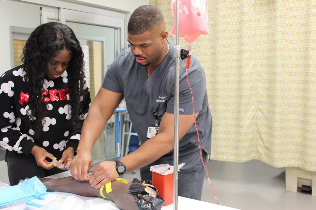 Medical student showing a young lady how to install an IV