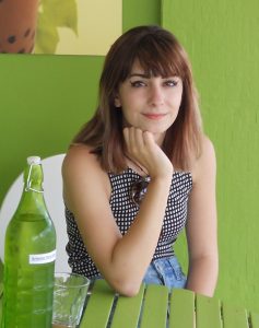 Young lady seated at table with green background