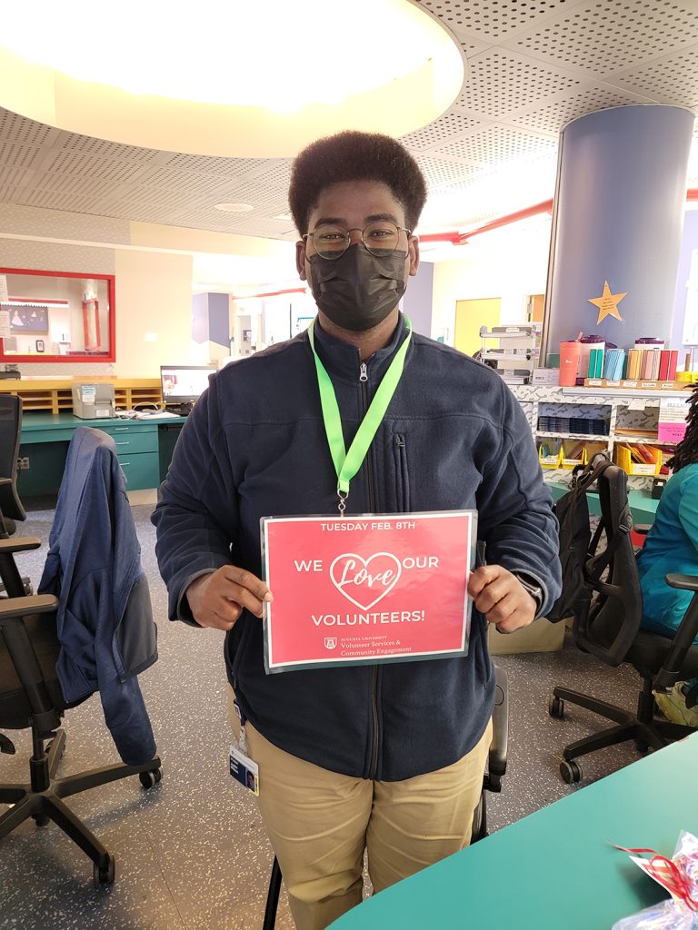 a student holds a sign that reads "we love our volunteers!"