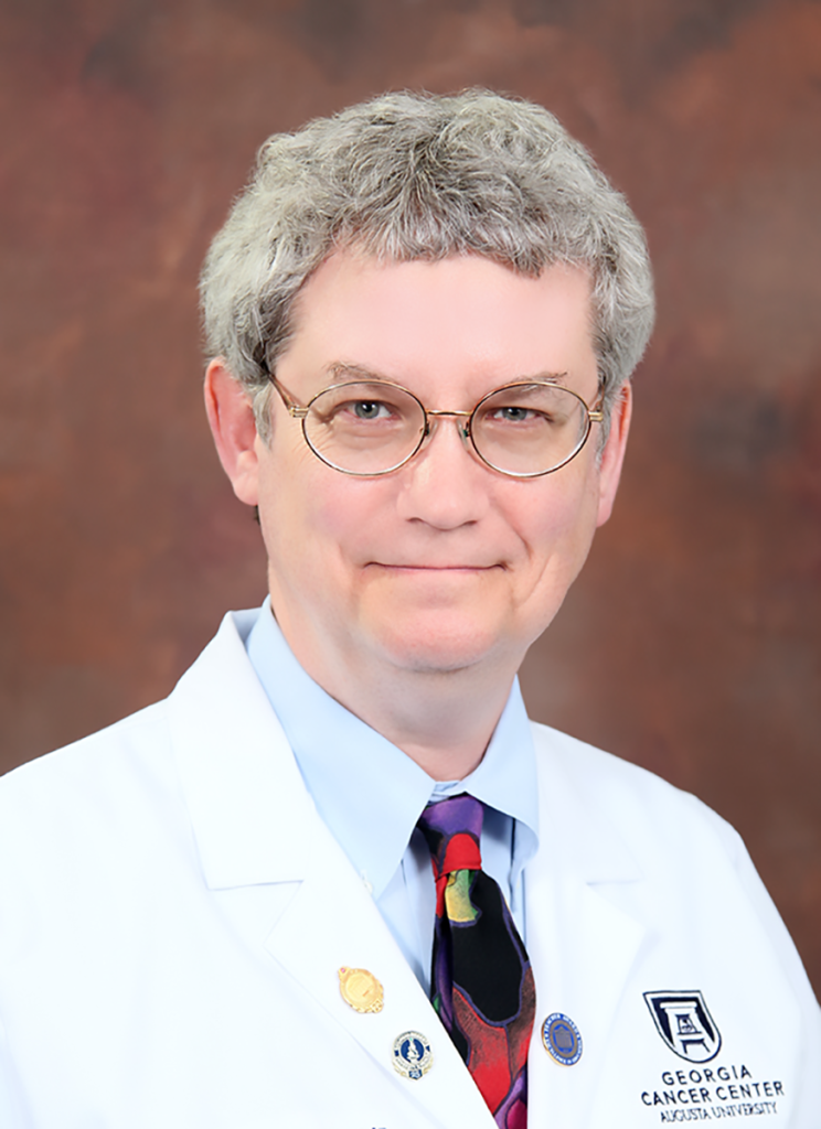 man in white doctor's coach stands in front of a textured background for a photo