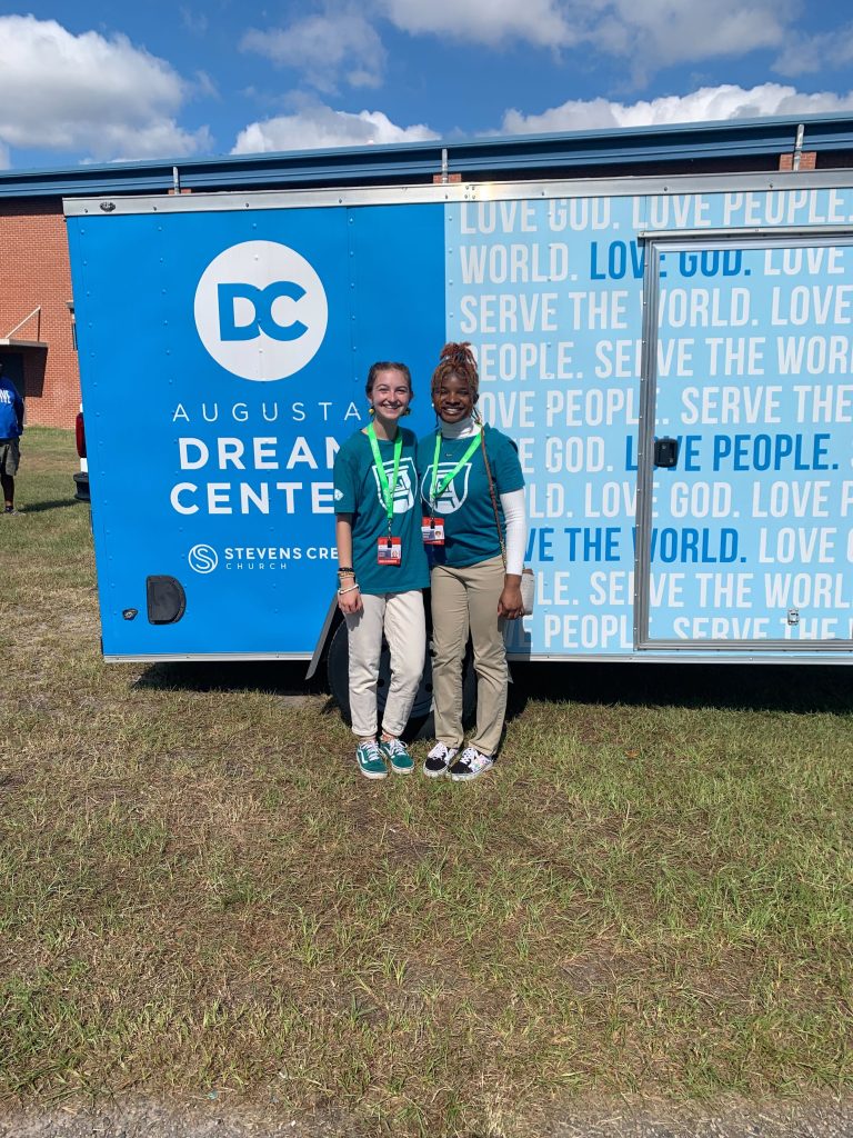 two women stand in front of a Dream Center trailer