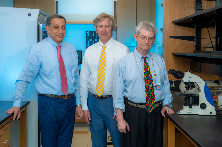 three men stand in a science lab