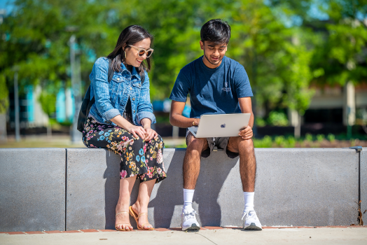 man and woman on the Health Sciences Campus looking at a computer