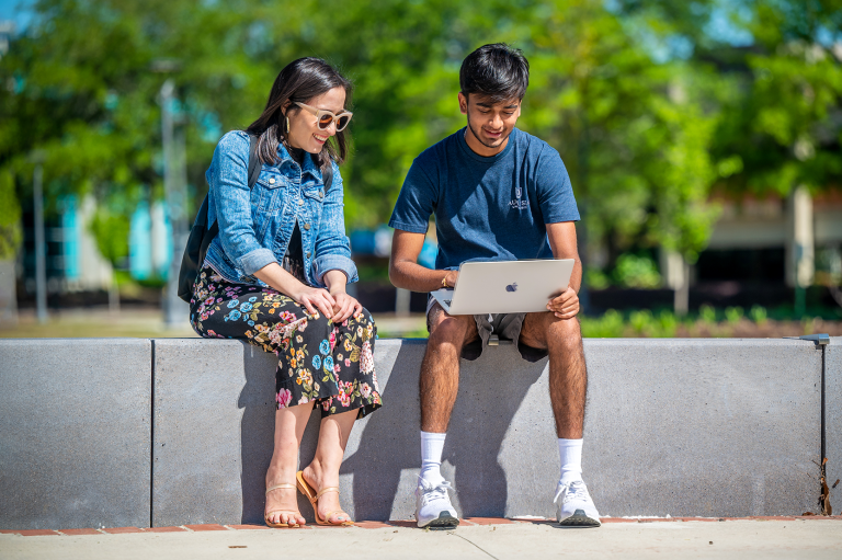 man and woman on the Health Sciences Campus looking at a computer