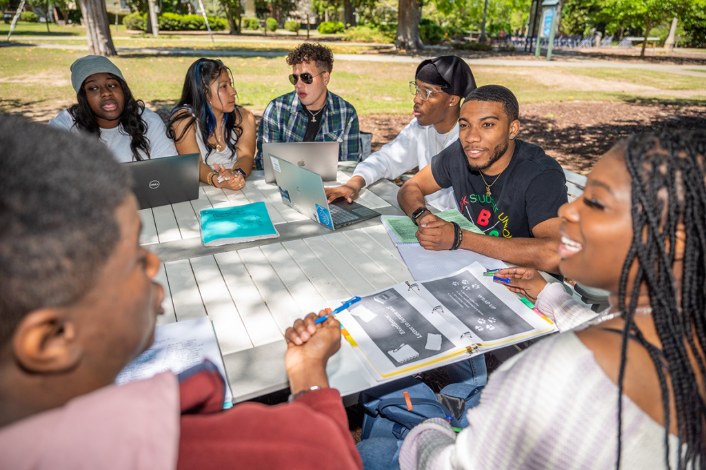 group of college students sitting at a picnic table outside