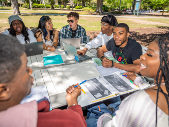 group of college students sitting at a picnic table outside
