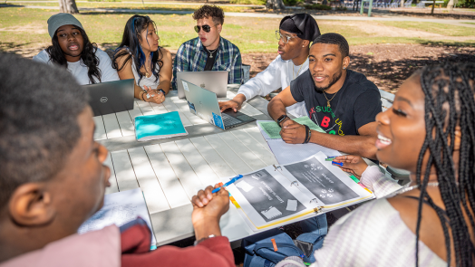 group of college students sitting at a picnic table outside