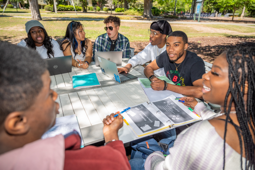 group of college students sitting at a picnic table outside