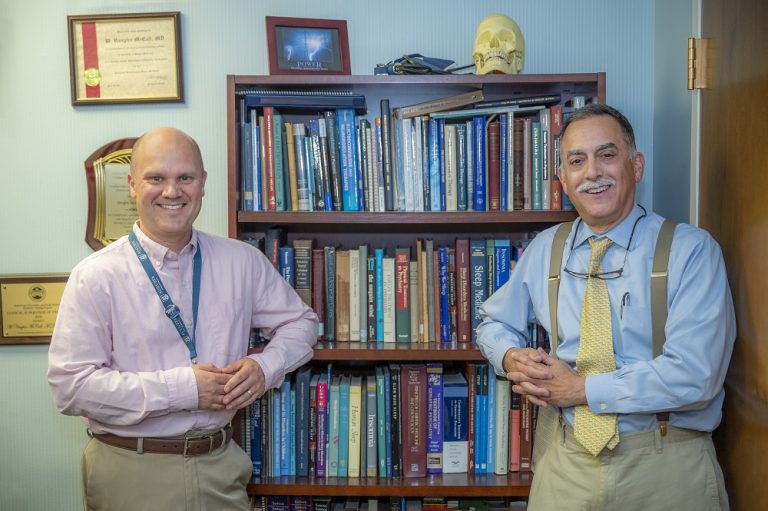 Two men smile and pose for camera.