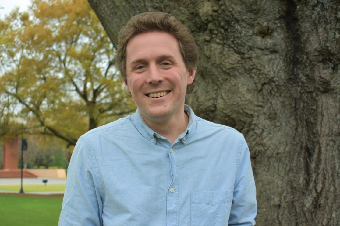 man smiling in front of tree