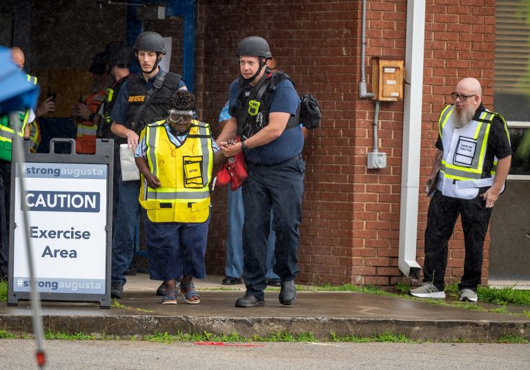 Emergency personnel escort an actor portraying a victim out of a school