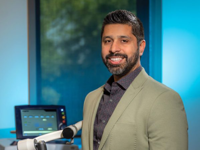 man stands in a scientific lab smiling