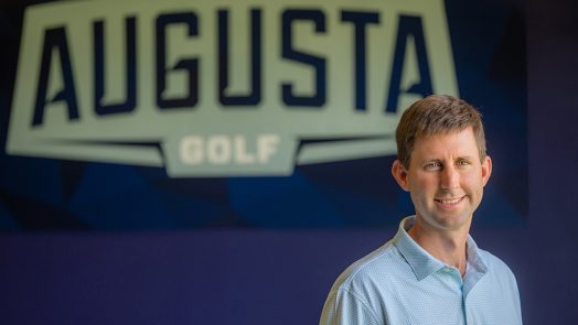 Man smiling in front of a sign