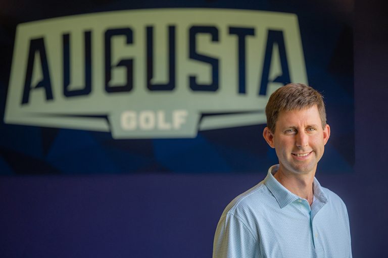Man smiling in front of a sign