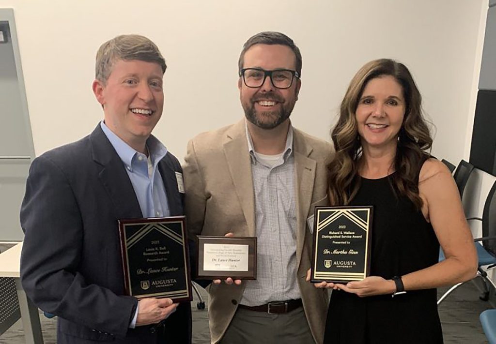 Two men and a woman with awards